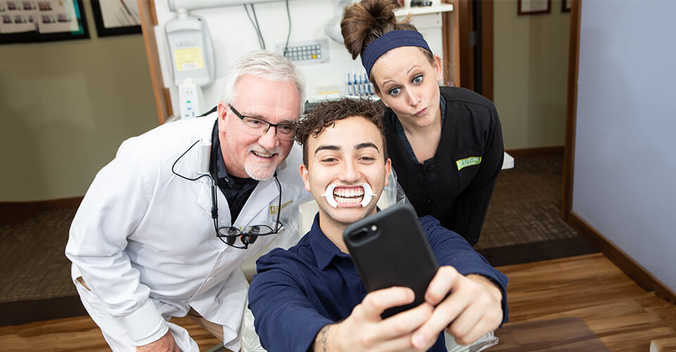 Dr. Wayne Kinney, our dentist in Indianapolis, IN, taking a selfie with patient and dental staff